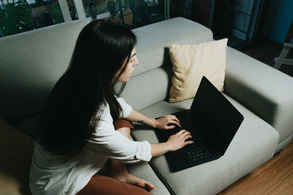 Female blogger blogging on a couch.