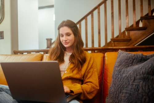 A blogger using a laptop to blog from the comfort of a couch.