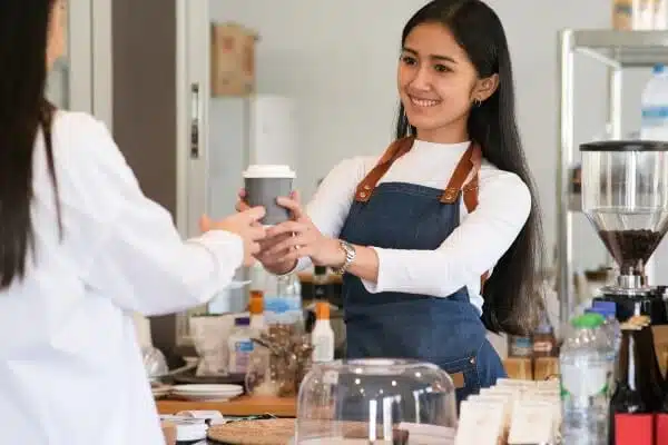 A friendly small business barista serving coffee to a customer.